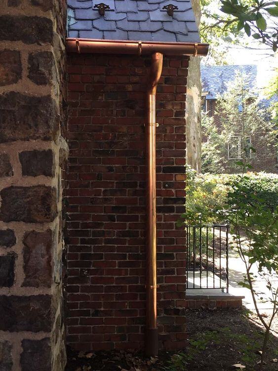 A copper downspout on a traditional brick house