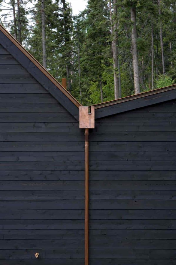 A dark rustic home in the mountains with copper rain gutters