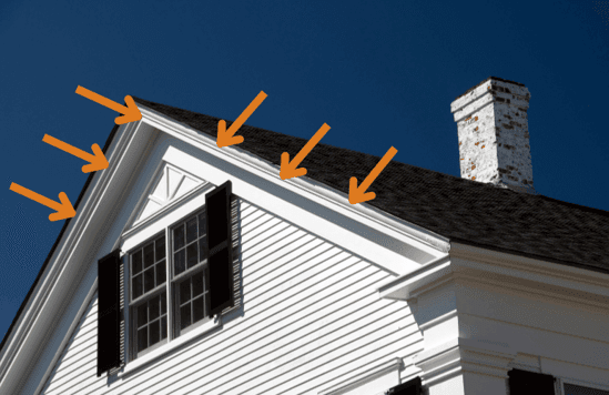 A white home with a black roof and orange arrows pointing to the fascia boards on the home.