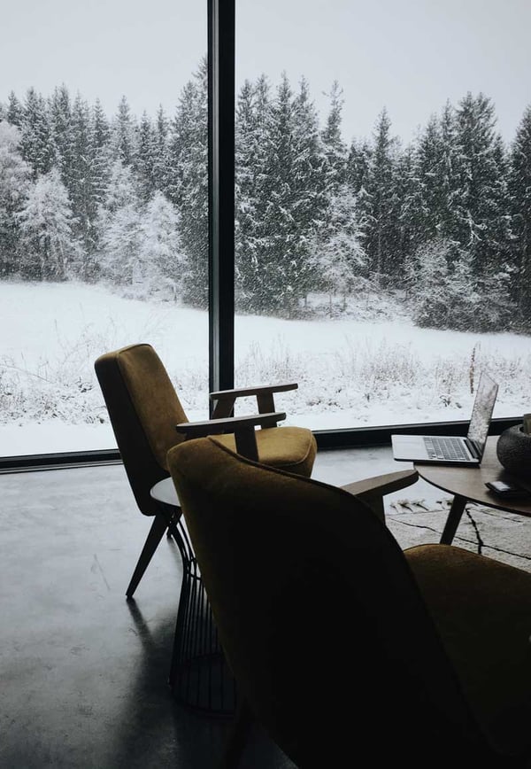 A mountain home office with a large window looking out on a beautiful snowy mountain landscape