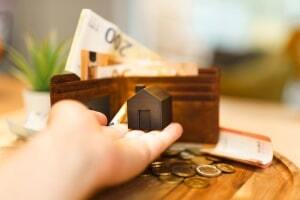 Person Holding Small House and Money Around It