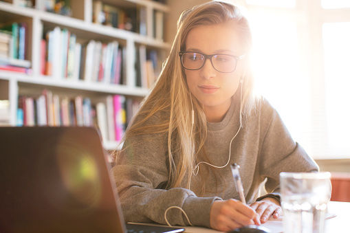 This is a picture of a blonde-haired white woman studying at a desk in front of a laptop.