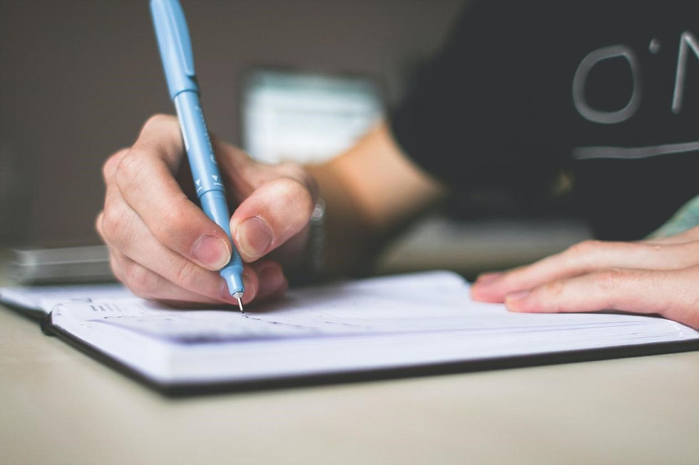 This is a picture of a student sitting at a desk, writing in an open notebook.