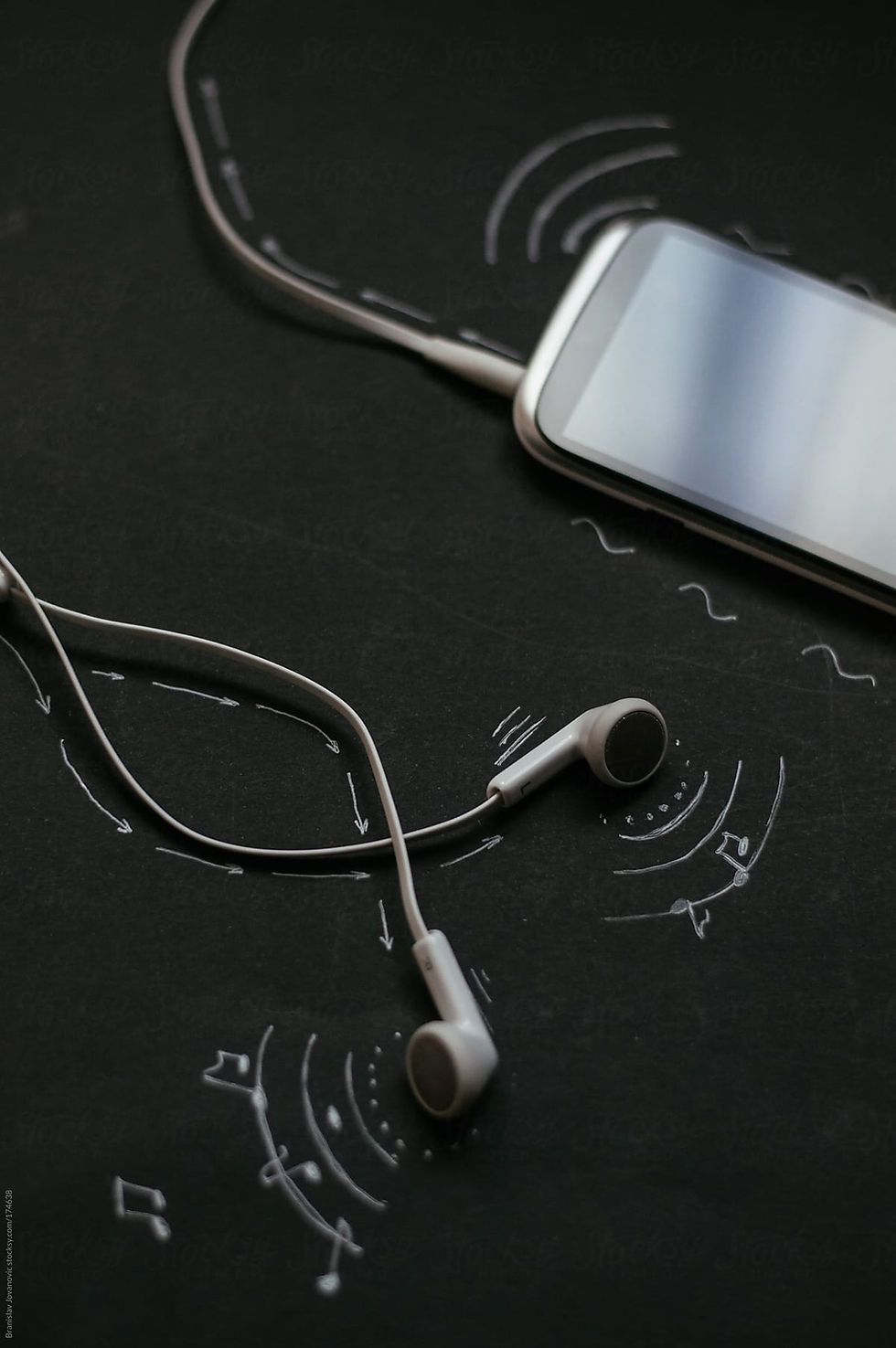This is a picture of a black cell phone connected to black earbuds. The items are resting against a black background.