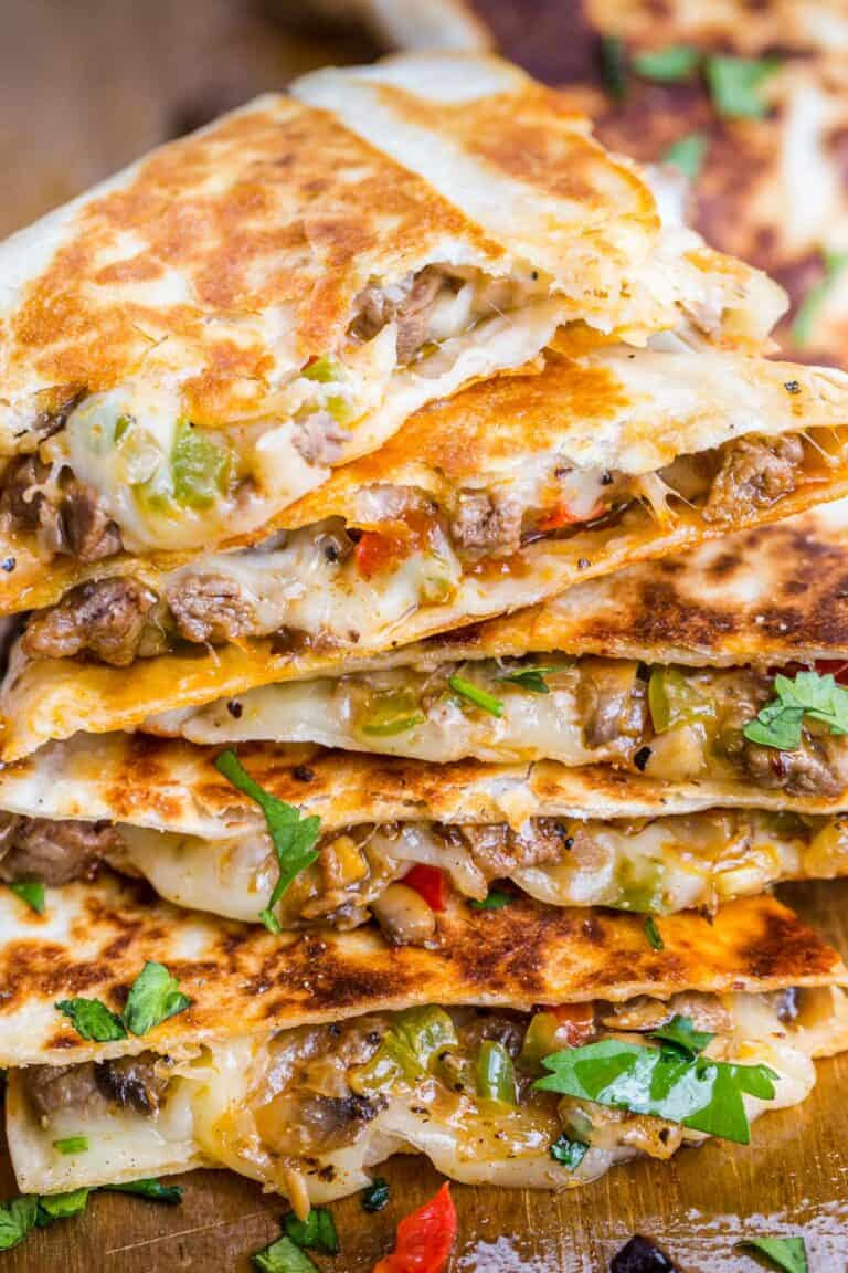 This is a picture of a stack of Cheesesteak Quesadilla. It has beef, cheese, and herbs inside, and each slice is wrapped by a toasted tortilla.