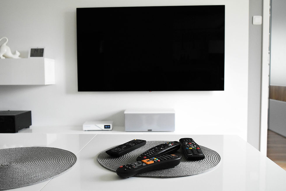 This is a picture of a Television mounted on a wall with four remote controls on the coffee table in front of it. 