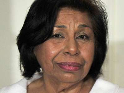 This is a portrait shot of Sylvia Mendez, an older Mexican woman. She's wearing a white shirt, and she has shoulder-length black hair.