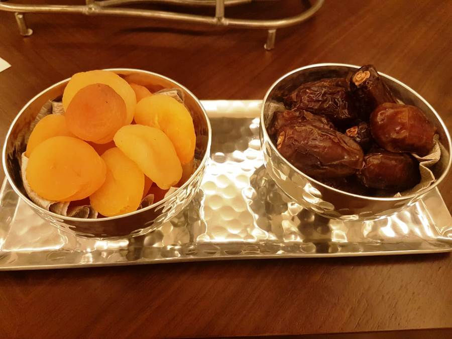 This is a picture of two small dishes. One has dried apricots, and the other has dried dates. 
