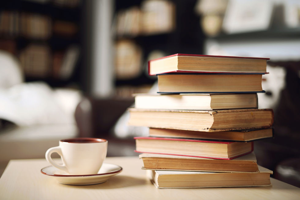 This is a picture of a stack of books next to a teacup and saucer.