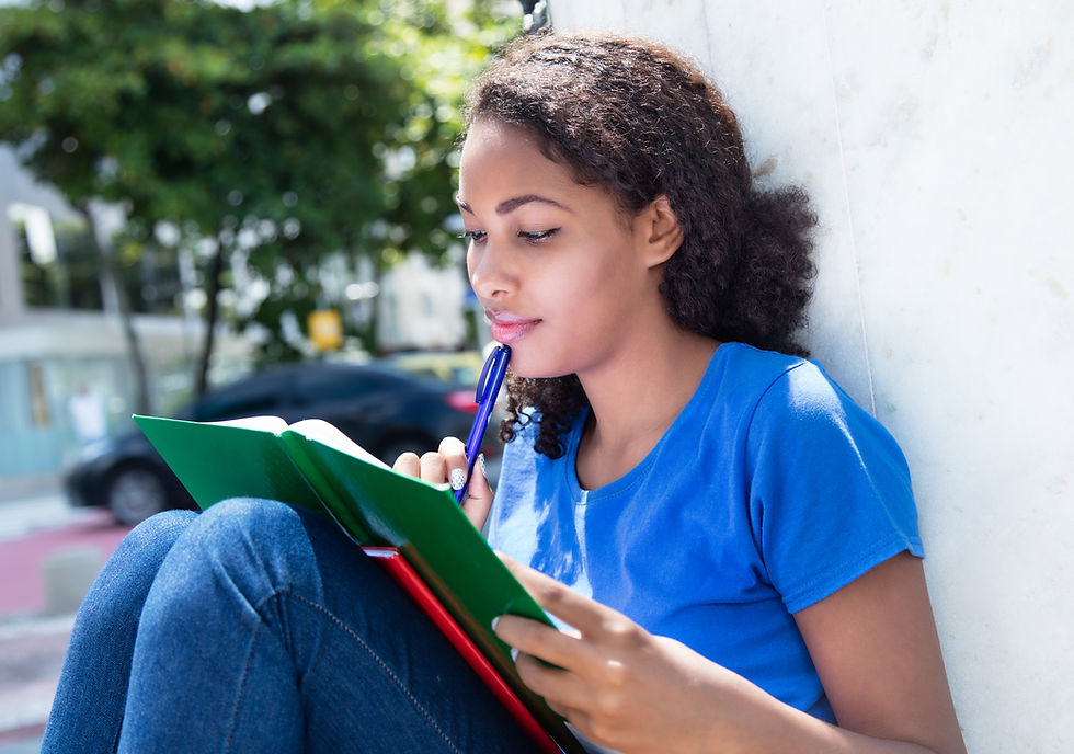 This is a picture of a Black woman sitting outside and studying. 