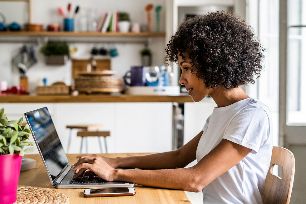Woman with light brown skin and dark curly hair reading a job ad online while looking at her laptop.