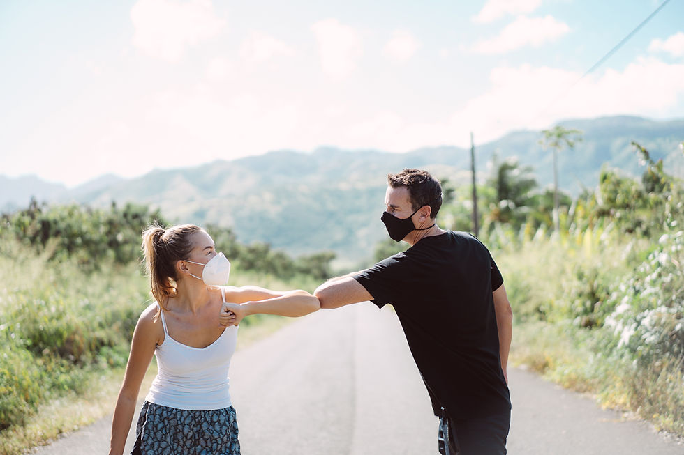 This is a picture of a man and a woman outside. They're both wearing masks and bumping each other's elbows.