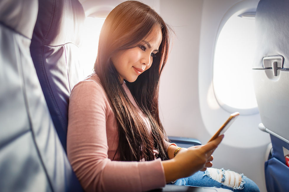 This is a picture of a woman sitting in an airplane, looking at her cell phone. 