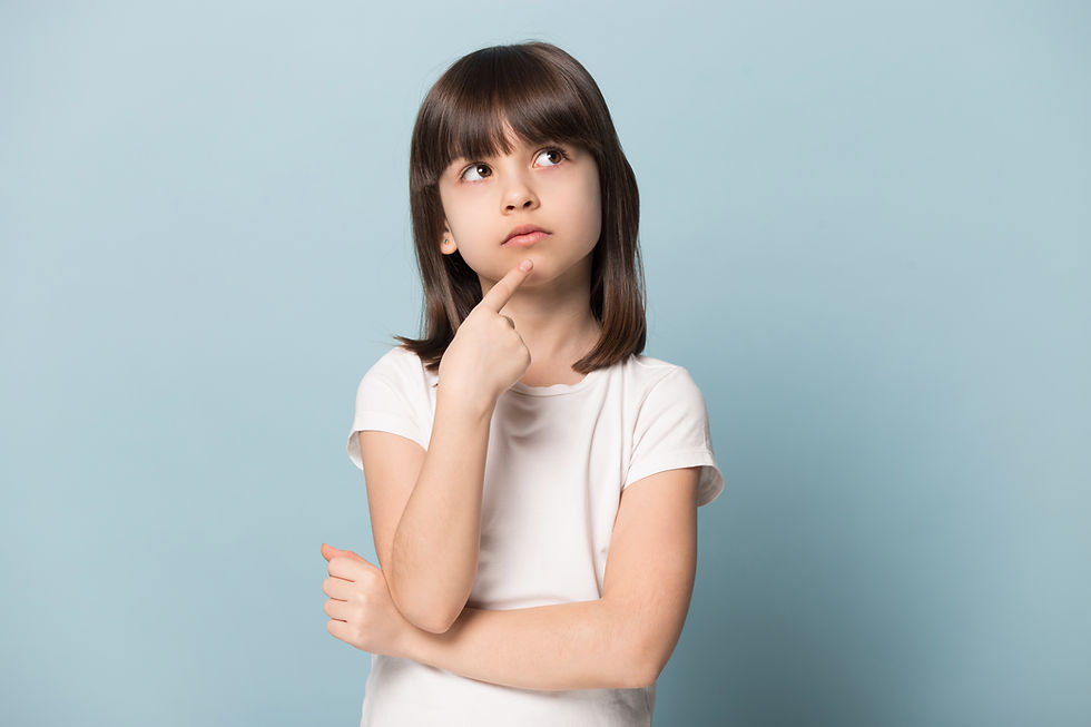 A young girl is against a light blue-gray background. She's only visible from the waist up, she has straight brown hair, and she's wearing a white t-shirt. Her left arm is resting in a straight line on her abdomen, her right elbow is resting on her arm, and her pointer finger is resting against her chin. She has a questioning look on her face. 