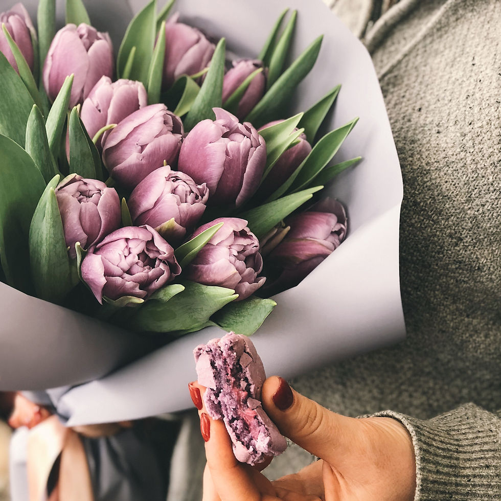 This is a picture of purple tulips and a half-eaten purple macaroon. 