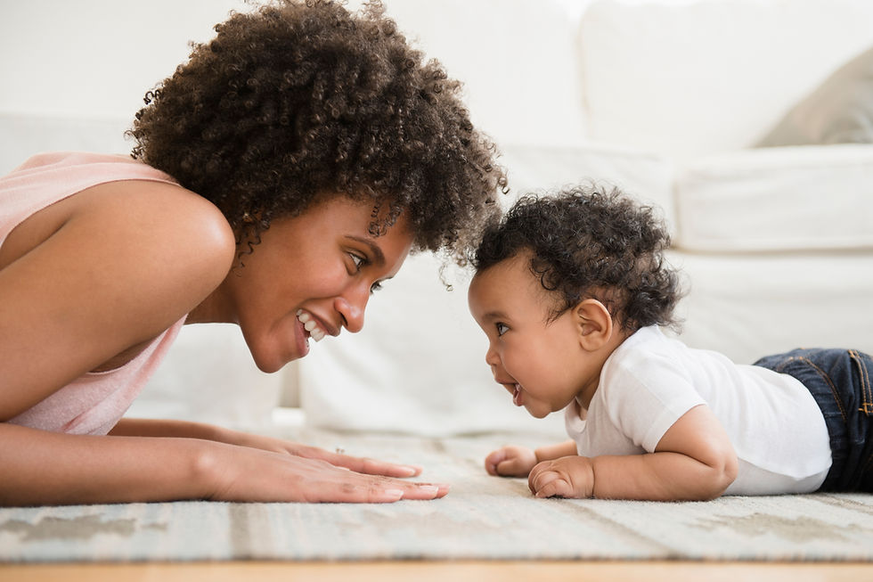 This is a picture of a mom and baby on the floor, playing with each other. 