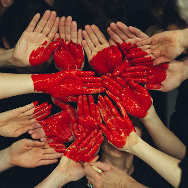 This is a picture of a bunch of outstretched hands. There is a painted heart over all of the hands, as though they were a canvas.