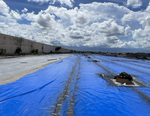 A job site with a sub-slab area is pictured, and there are white clouds in a blue sky.