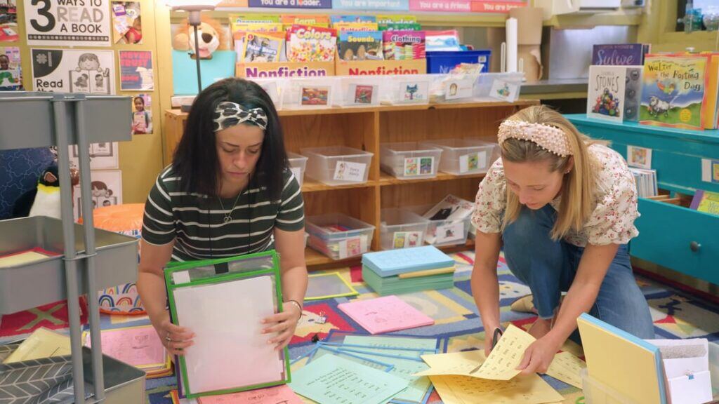 a first grade teacher and her mentor kneel on the floor of a classroom sorting through materials in a scene from the Right to Read documentary film