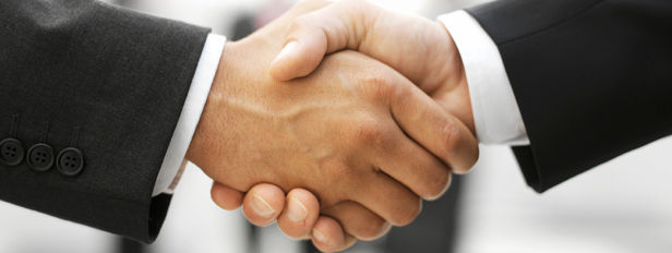 A picture of two men in suits shaking hands. 